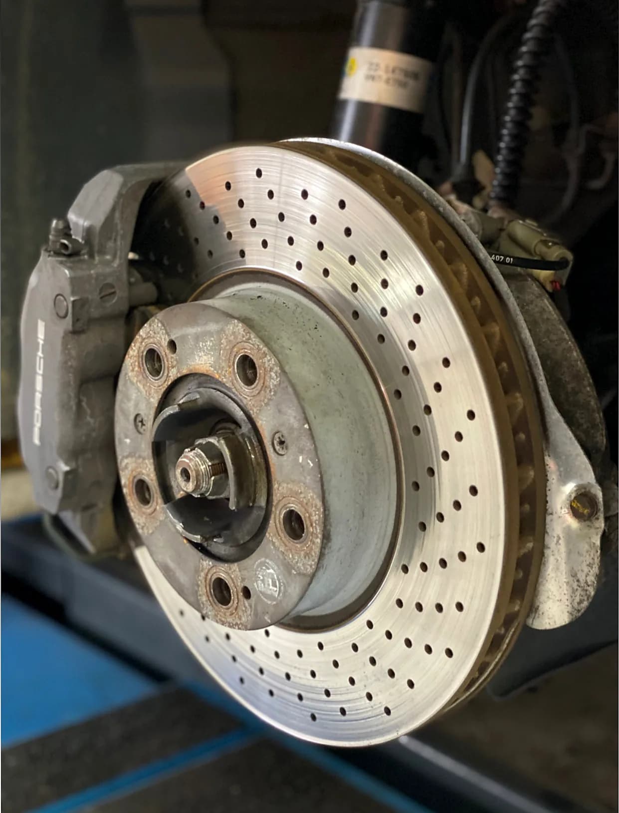 Porsche Bremssattel demontiert mit gelochter Bremsscheibe in der Werkstatt