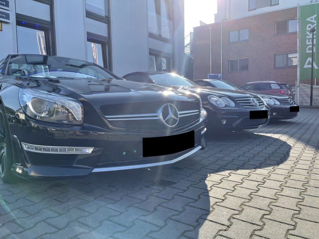 Mercedes AMG-Flotte vor der Werkstatt, DEKRA-Flagge im Hintergrund.