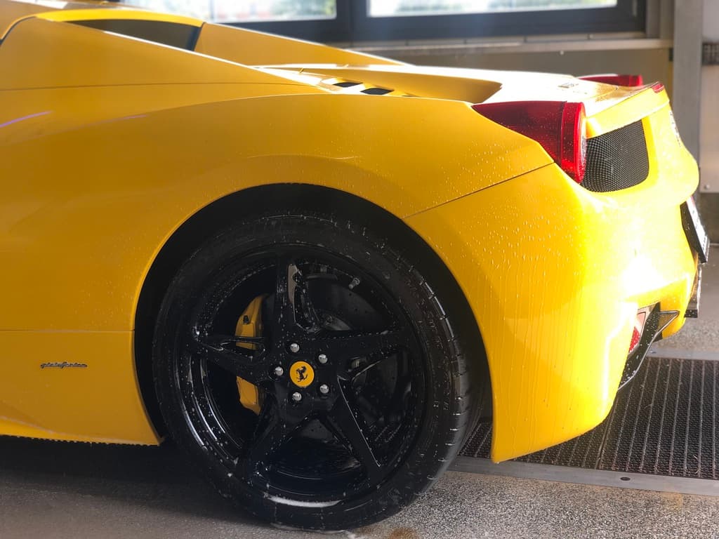 Gelber Ferrari 458 — Heck und Felge nass in der Waschbox.