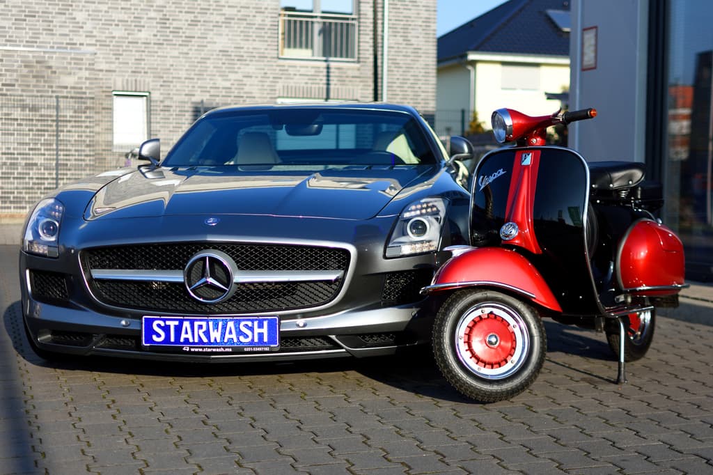 Mercedes SLS mit Vespa davor — Kontrast in der Halle.