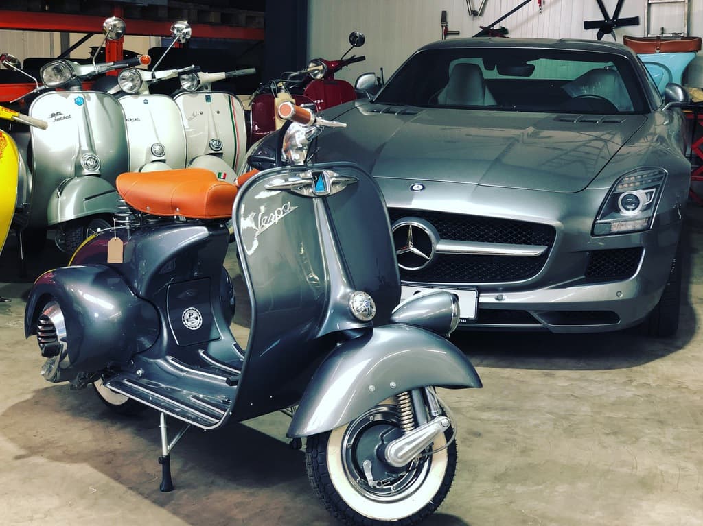 Vespa-Roller vor dem Mercedes SLS in der Halle.