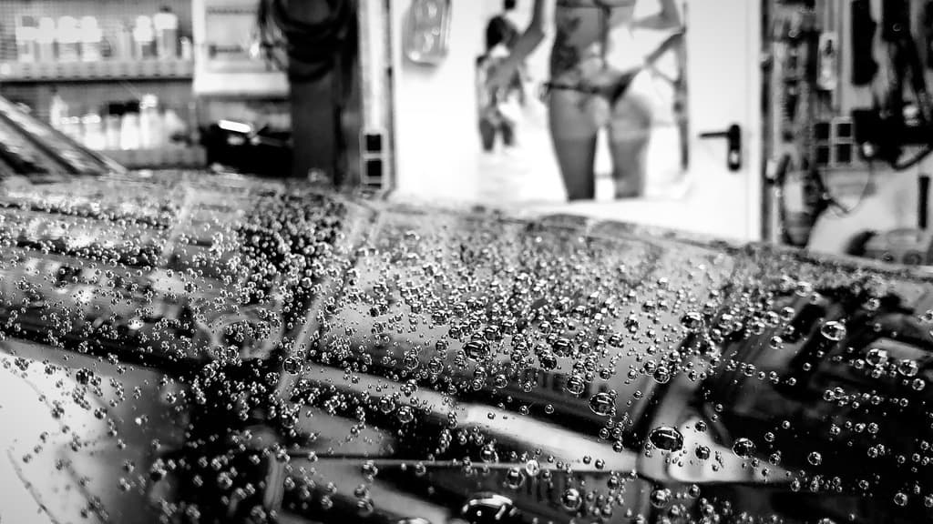 Wassertropfen auf Lack — Nahaufnahme in Schwarzweiss.